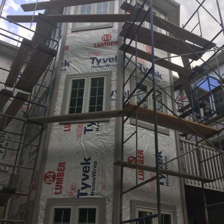 Siding repair in progress: house covered in scaffolding and Tyvek