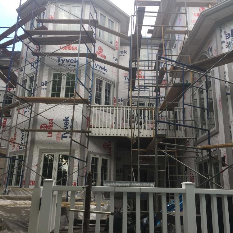 Ongoing siding repair: house covered in scaffolding, Tyvek