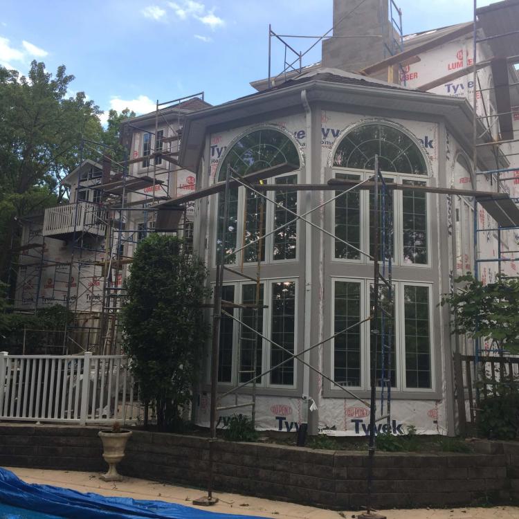 House getting a makeover due siding repair: scaffolding and Tyvek wrap