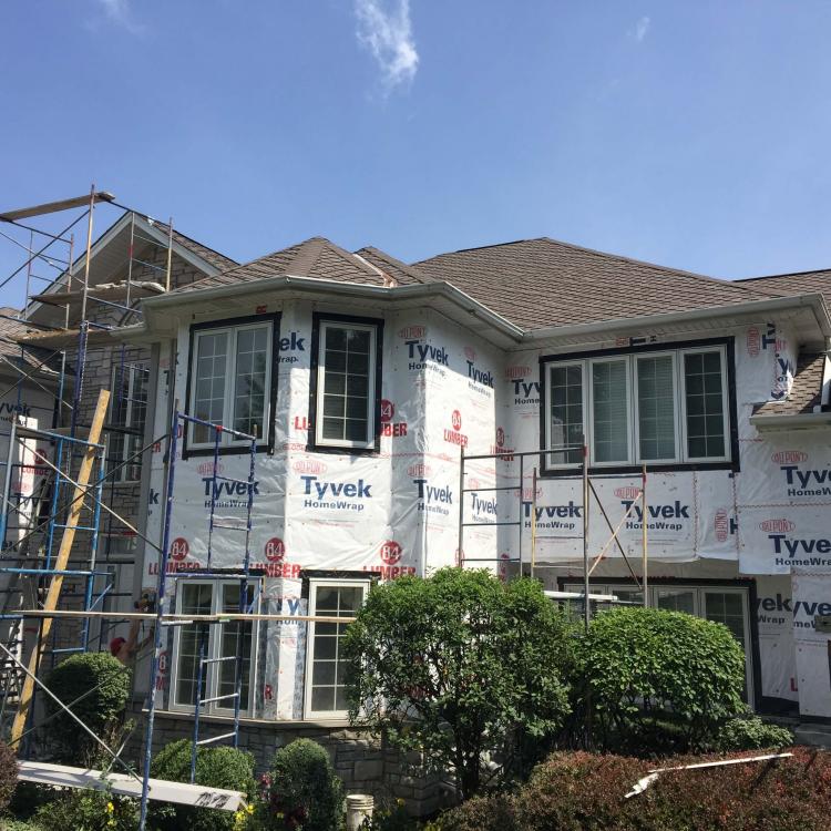 Home improvement project, siding repair, with scaffolding and Tyvek wrap