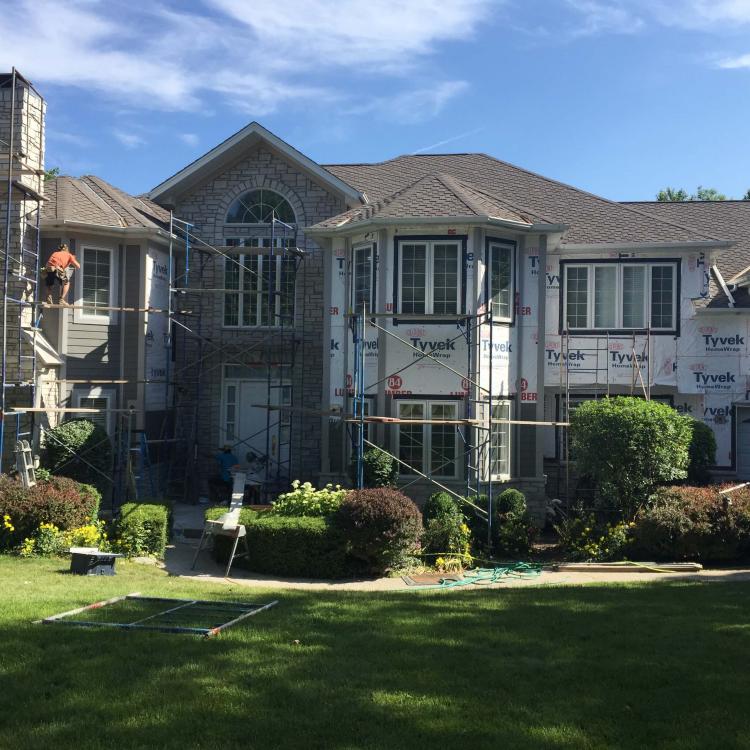 The exterior view of a house highlights the stone and siding repair.