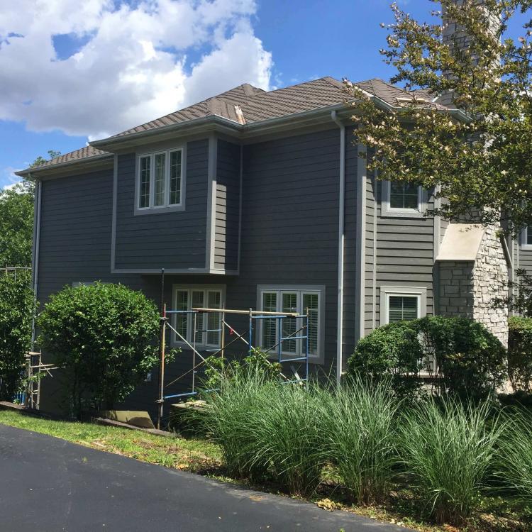 Exterior view of a gray house with scaffolding after siding repair works