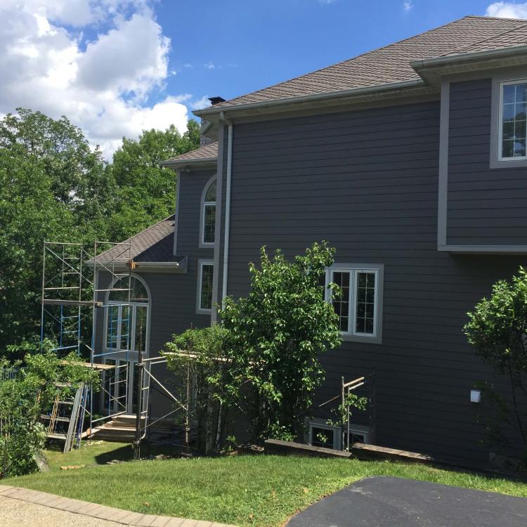 Exterior view of a gray house featuring scaffolding upon the completion of a siding repair project.