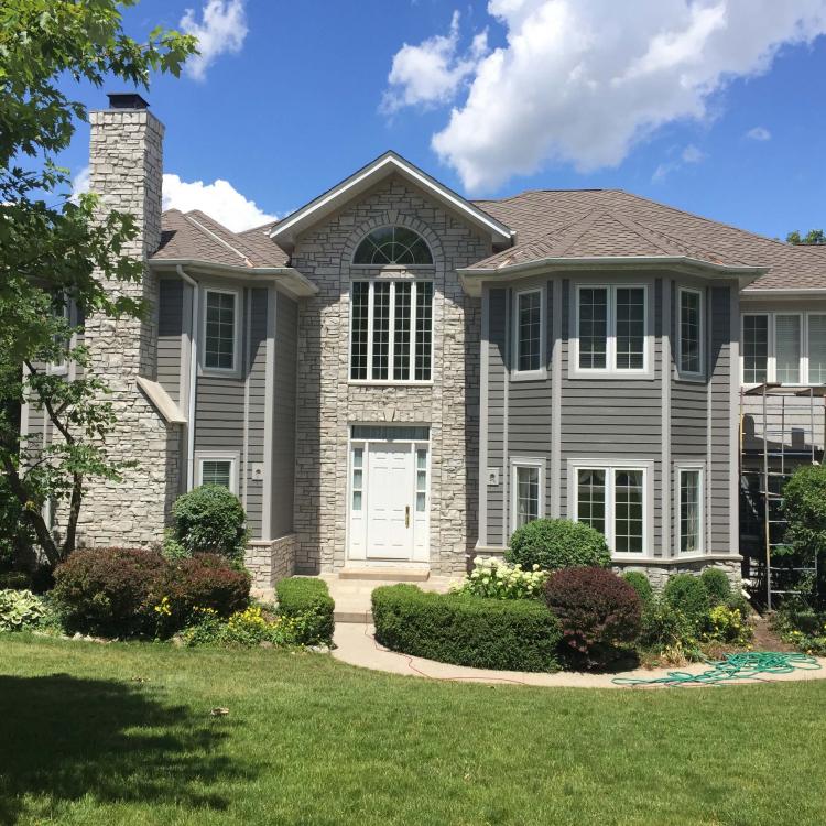 Exterior view of a house with gray siding. Scaffolding close to suggest siding repair is done