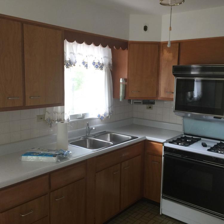 Outdated kitchen with wood cabinets and tile countertops.