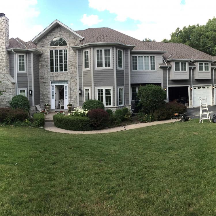 Exterior view of a house with a lawn and landscaping after renovation with siding repair