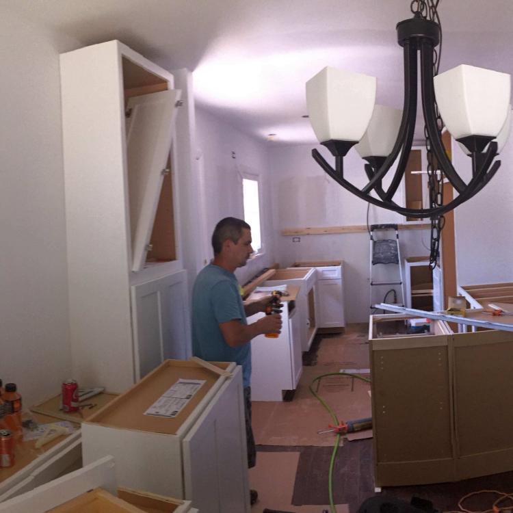 Kitchen remodel in progress: worker installing cabinets.