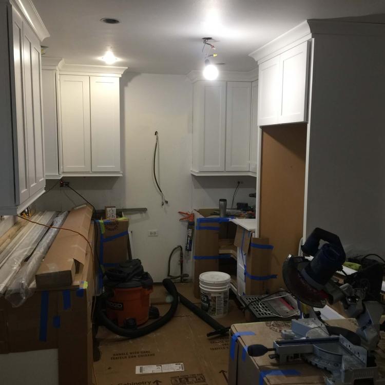 Kitchen remodel in progress: new cabinets installed, tools and materials on the floor.