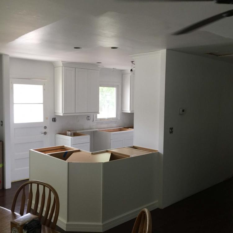 Kitchen remodel in progress: new white cabinets installed, countertops partially installed