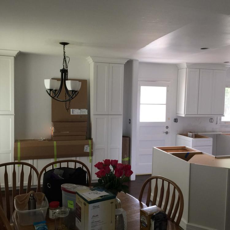 Kitchen remodel in progress: new white cabinets installed, countertops partially installed.