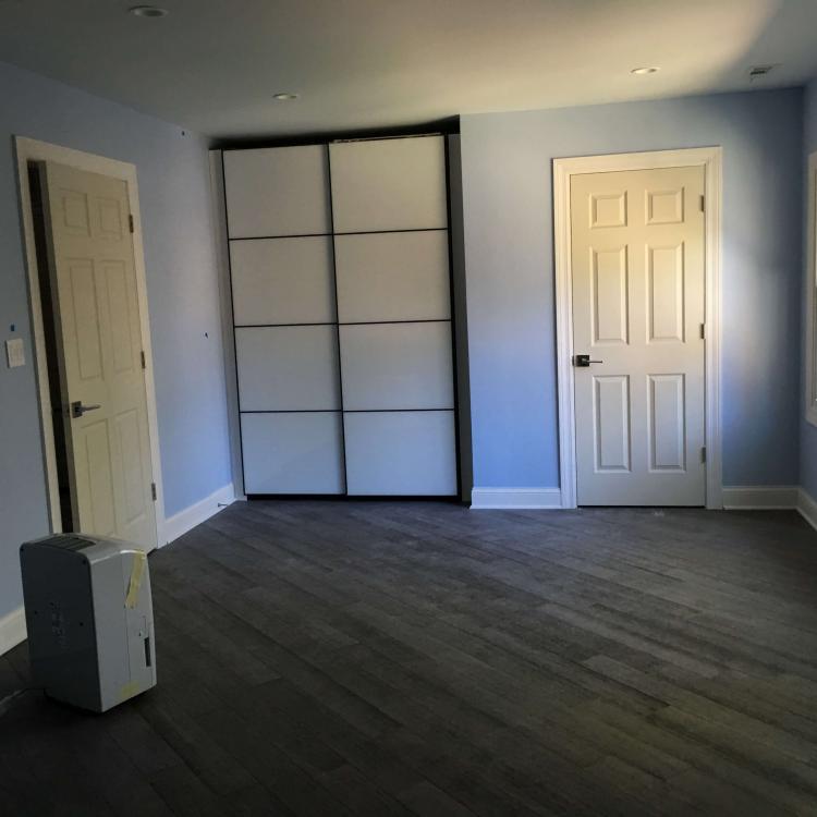 Renovated bedroom with light blue walls, sliding closet doors, and dark wood flooring