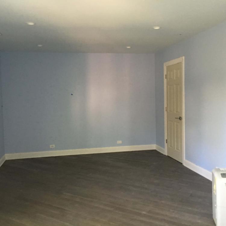 Newly renovated basement featuring light blue walls and dark wood laminate flooring.