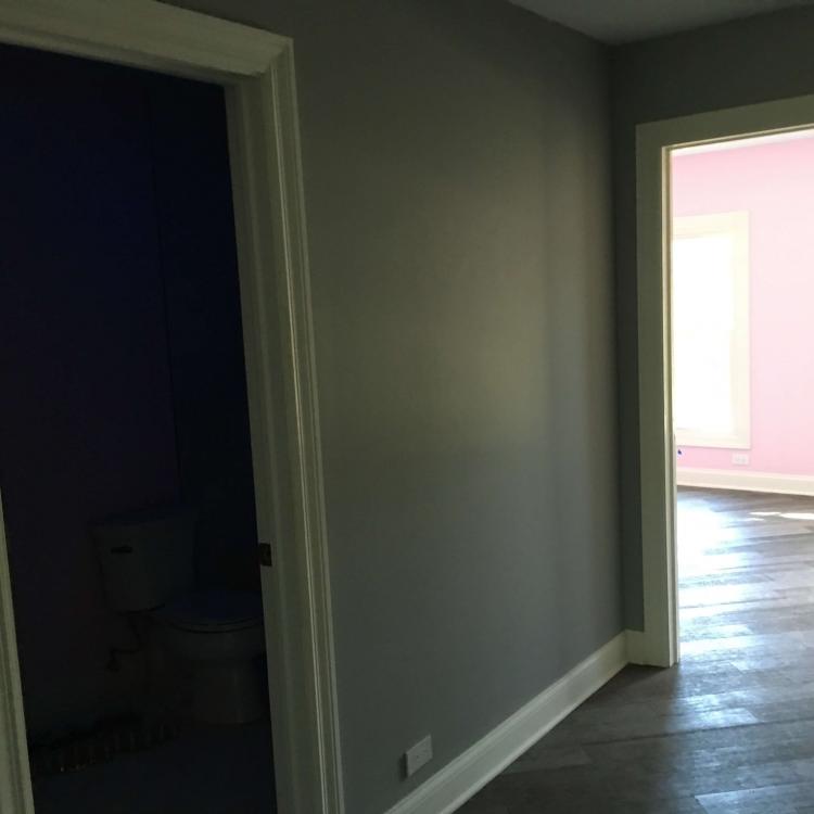 Completed hallway renovation with gray walls, hardwood floors, and white-framed doors