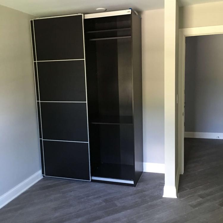 Completed bedroom renovation with a modern sliding closet and dark wood floors