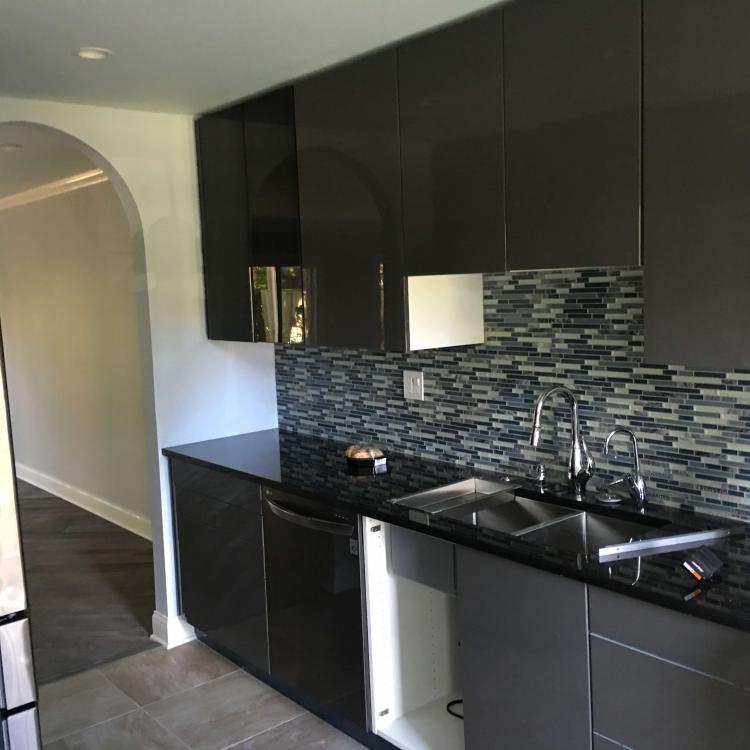 Renovated kitchen with dark gray cabinets, stainless steel appliances, and a glass tile backsplash