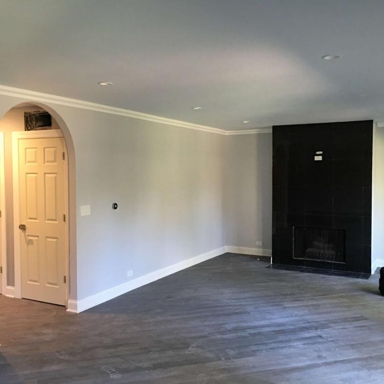 Newly renovated living room: painted walls, wood laminate flooring, and a black fireplace