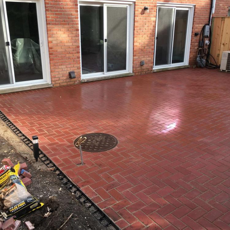 Completed backyard renovation with a brick paver patio.