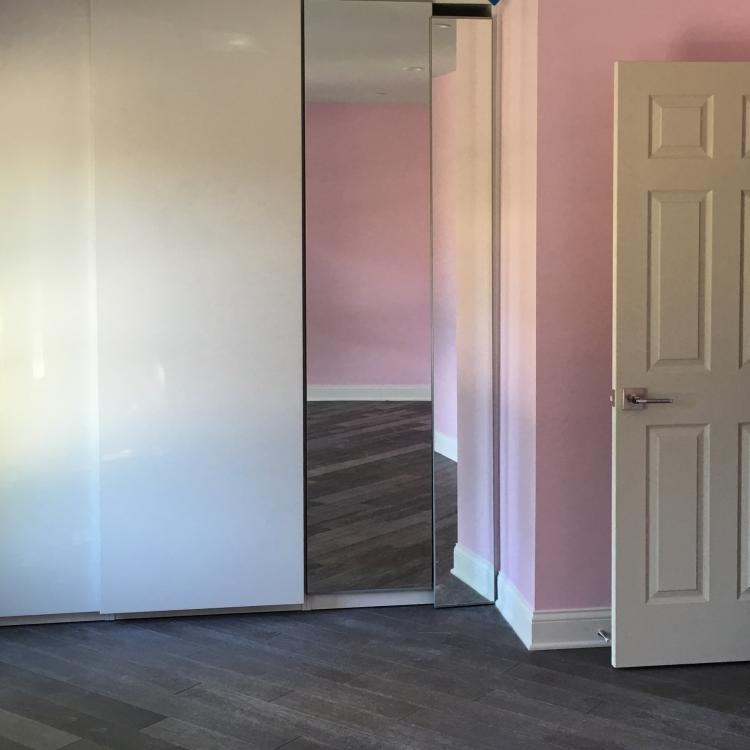 A bedroom with a sliding door, pink walls, and dark wood flooring