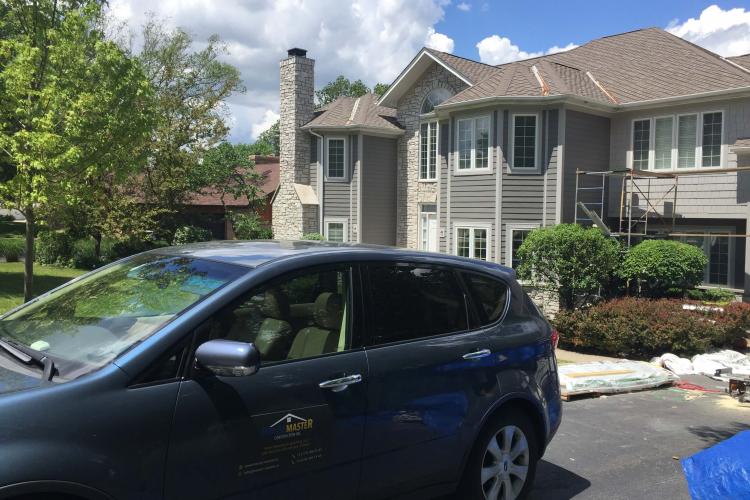 House exterior painting in progress: painters' car parked in driveway.