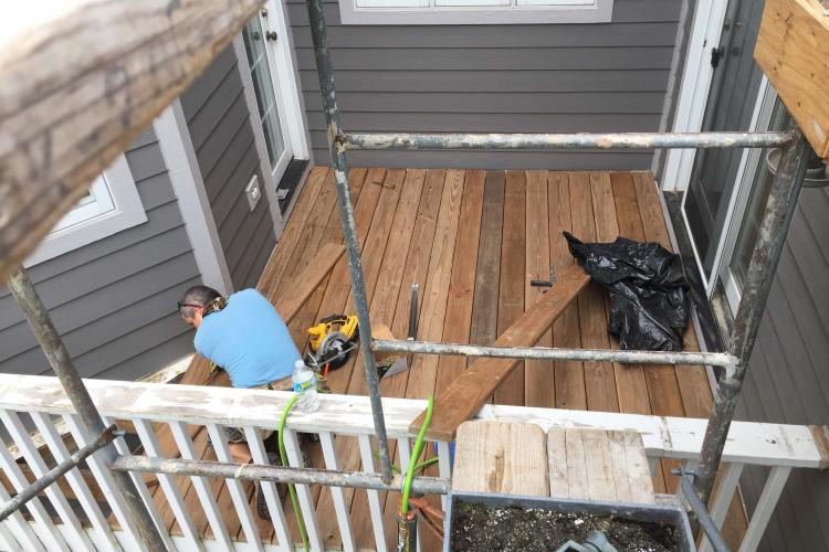 Deck repair and replacement in progress: Worker repairing a wooden deck