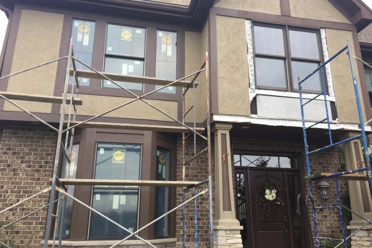 Window replacement in progress: House with scaffolding and new windows being installed.