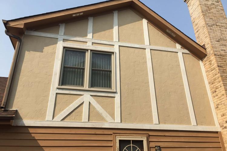 A house with stucco siding and a large window, showing repaired walls