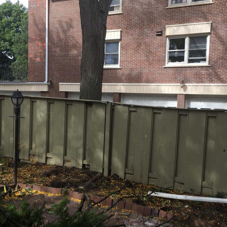 Wooden fence in need of repair due to leaning and damage.