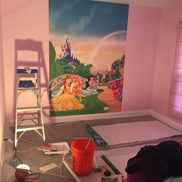 Custom mural installation in progress: princess wallpaper on pink wall.