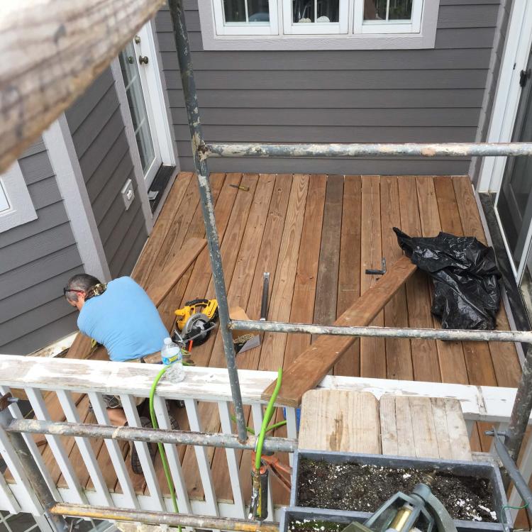 Deck repair and replacement in progress: Worker repairing a wooden deck