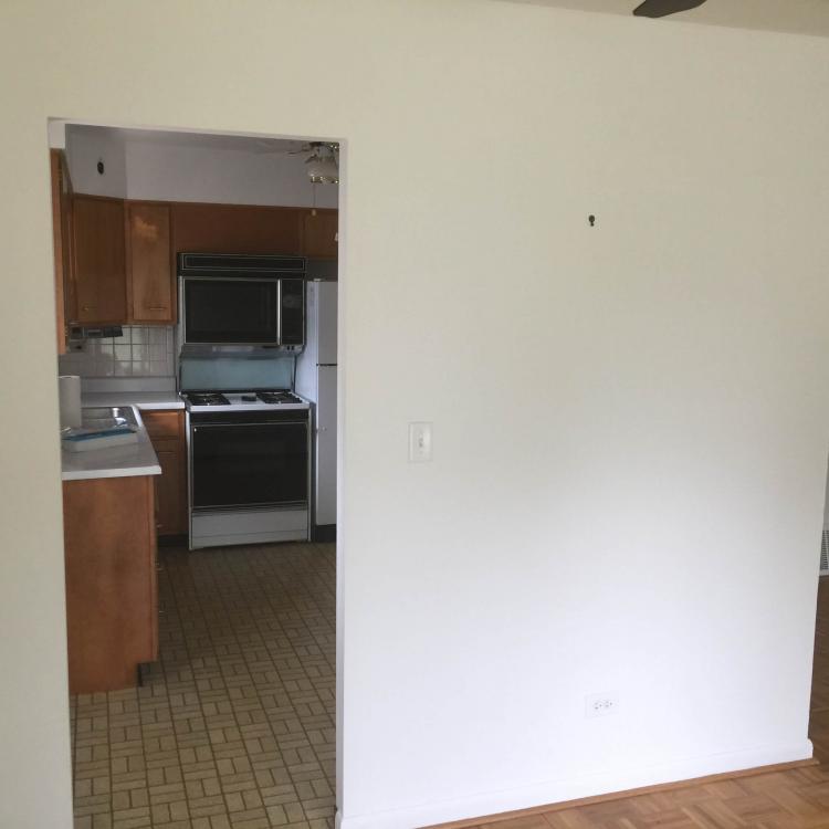 Open doorway leading to a kitchen with wood cabinets and appliances