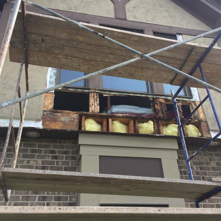 Window frame repair in progress: Damaged window frame being repaired with scaffolding