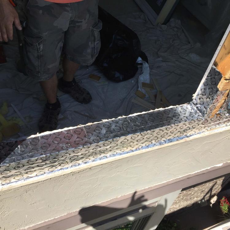 Window frame repair in progress: New flashing being installed around window frame.