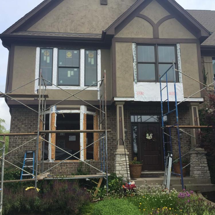 Window installation project: House with scaffolding and new windows being installed.