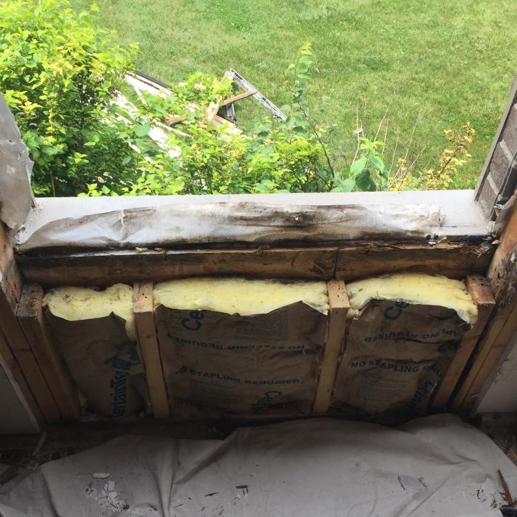 Window frame repair in progress: Damaged window frame showing water damage and rot.