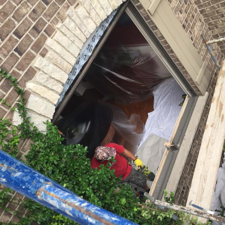 Window installation in progress: Worker installing a new window into a brick wall.