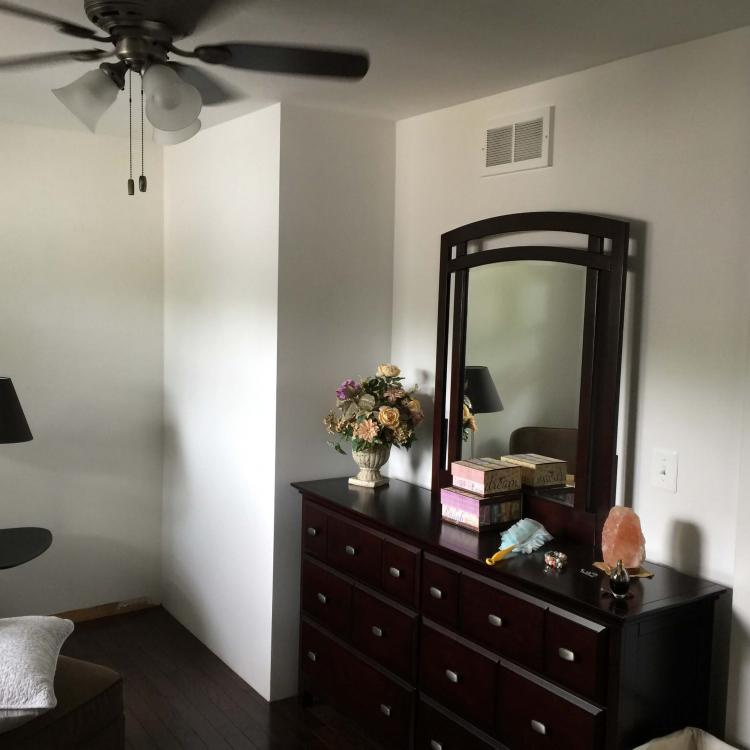 Bedroom interior with a bed, dresser, mirror, lamps, and a ceiling fan