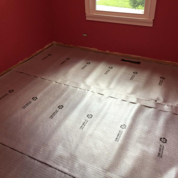 Laminate floor installation in progress: Underlayment being laid.