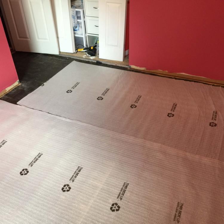 Laminate floor installation in progress: Underlayment being laid in a bedroom.