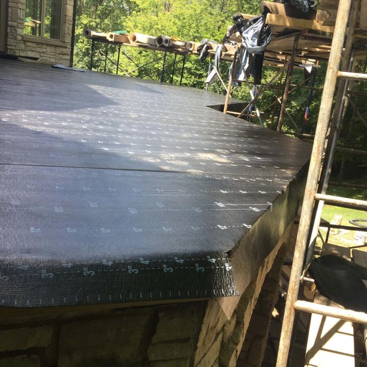 A deck under construction with a black waterproof membrane covering the surface