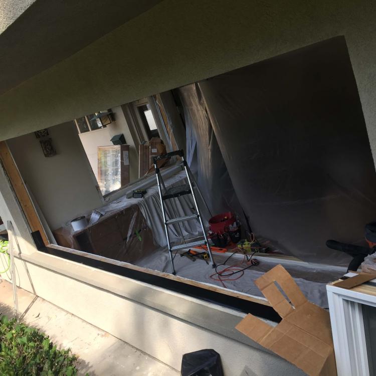 Exterior view of a window replacement project, showing the old window being removed