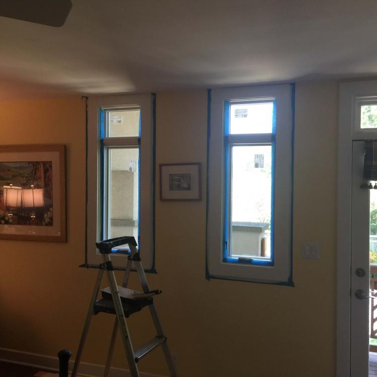 Interior view of a room with new windows being installed, with painter's tape around the frames