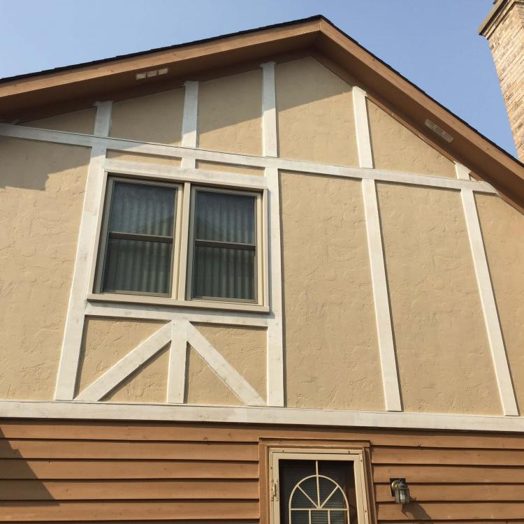 A house with stucco siding and a large window, showing repaired walls