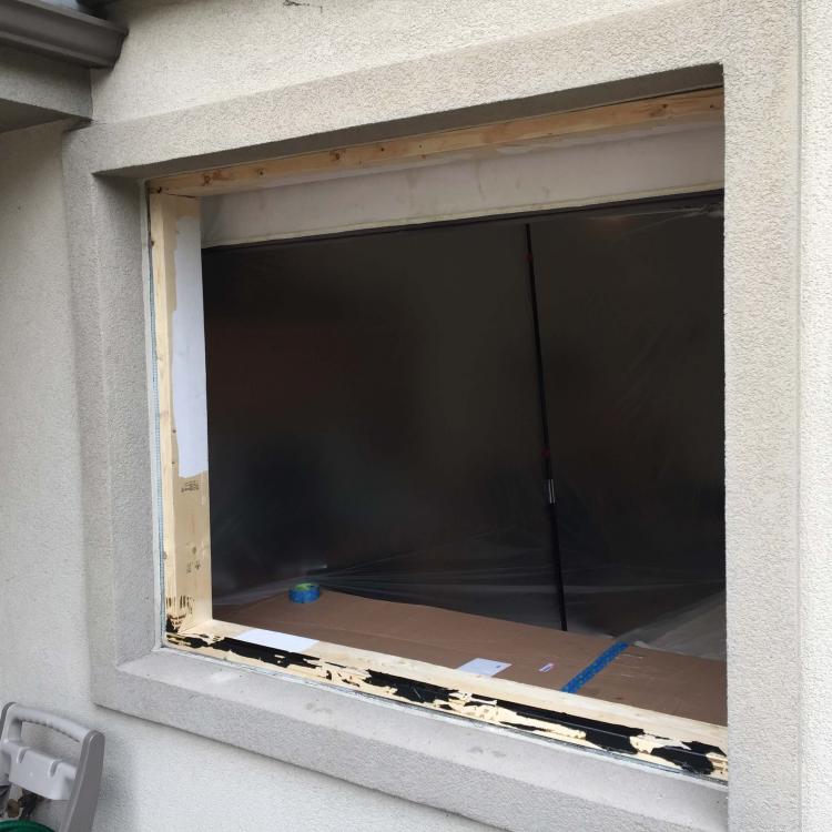 Exterior view of a window replacement project, showing the old window frame