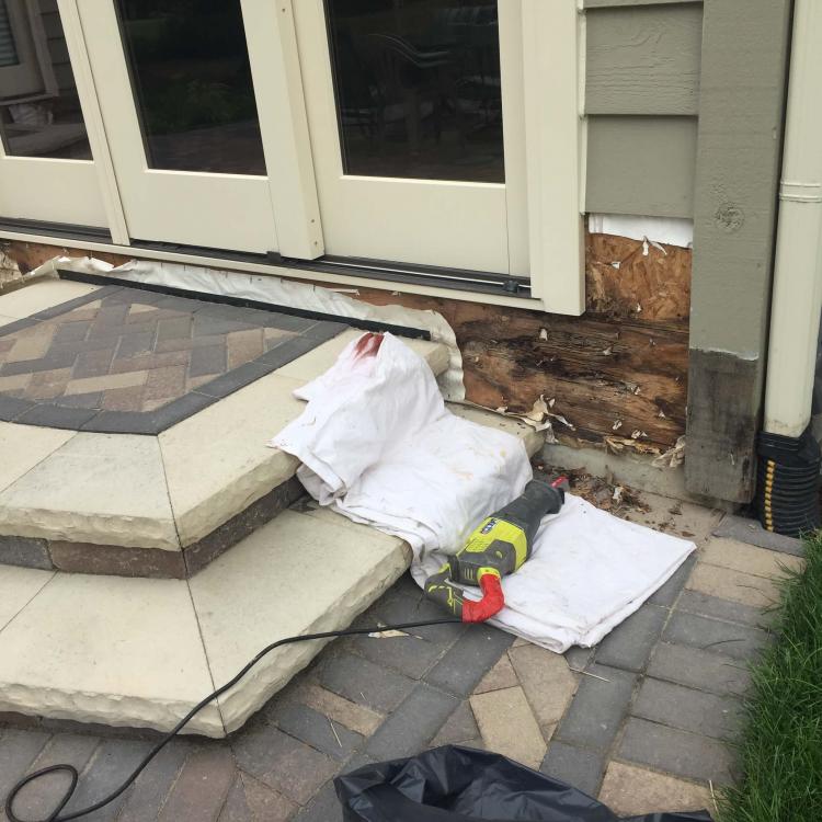 Damaged house exterior with exposed wood and insulation, before siding repair