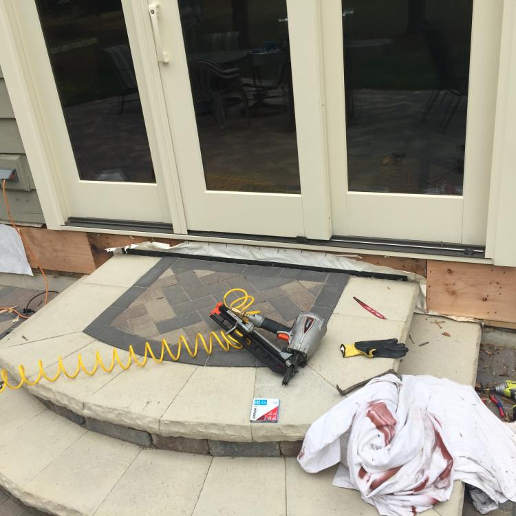 A patio door and surrounding siding with damage, indicating  siding repair or replacement works